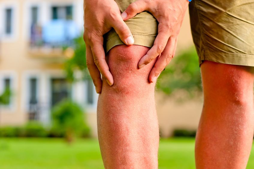 Photo of a man holding his knee due to arthritic pain