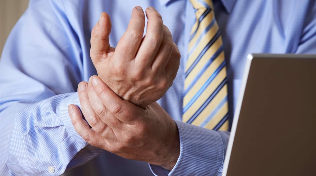 Photo of a man holding his wrist as if in pain due to carpal tunnel syndrome