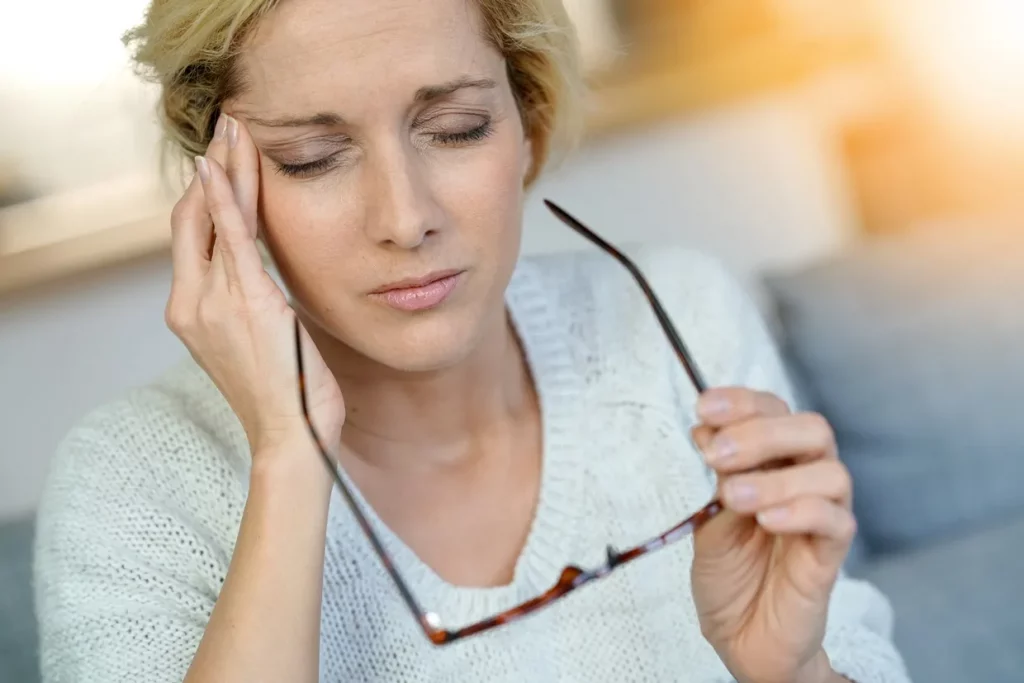 Photo of a woman massaging her temple seemingly due to a headache