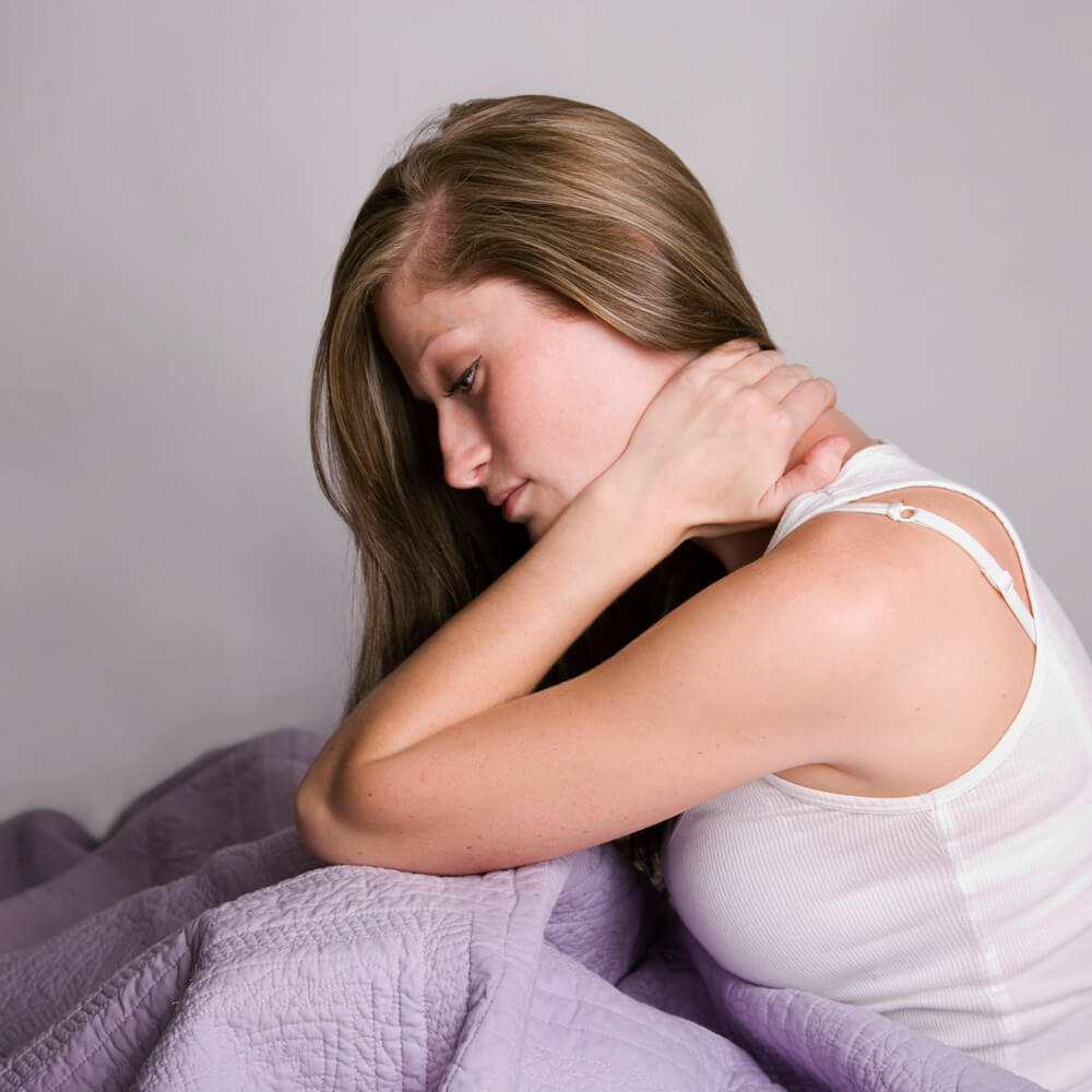 Photo of a woman massaging her neck seemingly due to pain