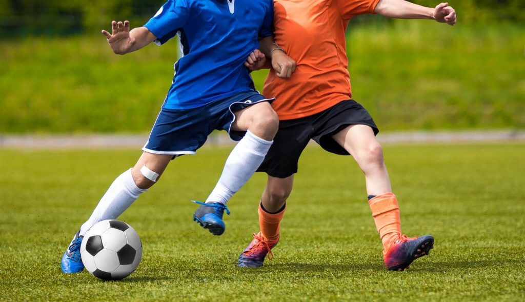 Two men playing soccer and on the verge of having an accident